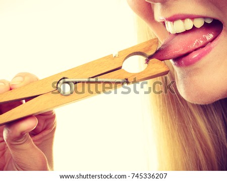 Language barrier, rumors, problems with expressing concept. Blonde woman having tongue in clothespin