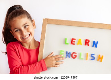 Language education concept. Learn English. Do you speak English. Cute little child girl with letters on the blackboard. English language school. English for children. - Shutterstock ID 1208949397