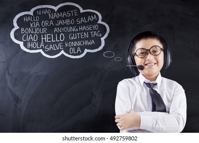 Language learning concept. Little boy standing in the classroom while wearing headphones and learn multilingual