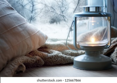 lantern and pillows on windowsill with winter view