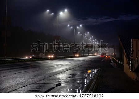 Lanterns along the road in a night city with puddles after rain. Horizontal orientation. 