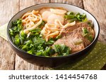 Lanzhou beef noodle soup is a type of Chinese ramen noodle soup with beef slices served on the top closeup in a bowl on the table. horizontal
