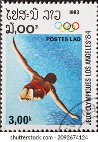 Laos - Circa 1983: A Post Stamp Printed In Laos Showing An Athlete  Diving High Tower During The Summer Olympic Games 1984 - Los Angeles