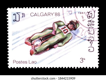 Laos - Circa 1987 : Cancelled Postage Stamp Printed By Laos, That Shows Toboggan And Promotes Winter Olympics In Calgary, Circa 1987.