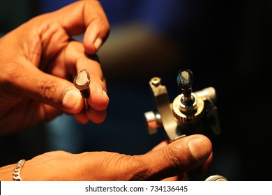 A Lapidarist Comparing The Cut Of Two Gemstones