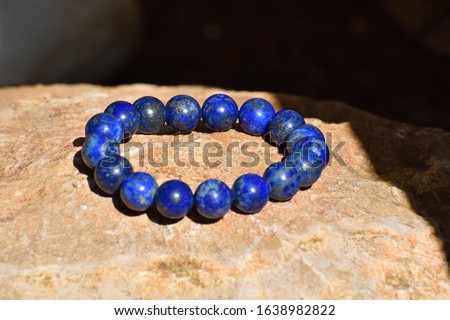 Lapis lazuli bracelet on a stone or rock in the garden with copy space. Selective focus.
