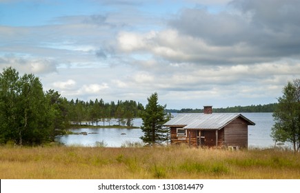 Lapland Summer Landscape. Beautiful Small Wooden House On The Lake Shore, Finland.