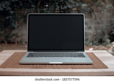 Laptop with black screen on wooden table - Shutterstock ID 1837577596