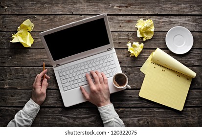 Laptop with blank notepad and pencil with sheets of crumpled paper on old wooden table. Top view of workplace writer. - Powered by Shutterstock