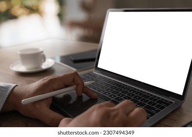 Laptop with blank screen on table interior, man at his workplace using technology
