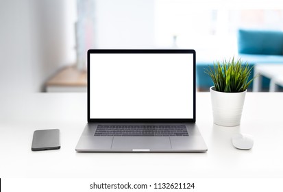 Laptop with blank screen on white table with mouse and smartphone. Home interior or office background - Powered by Shutterstock