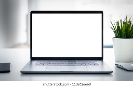 Laptop with blank screen on white table with mouse and smartphone. Home interior or office background