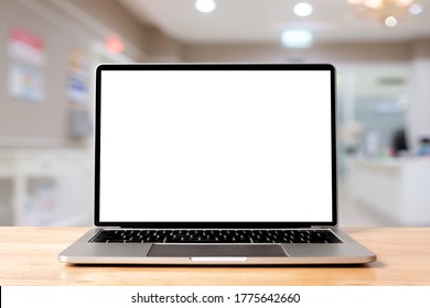 Laptop Blank Screen On Wood Table With Hospital Or Clinic Background, Mockup, Template For Your Text, Clipping Paths Included For Background And Device Screen