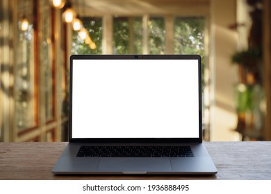 Laptop with blank screen on wood table in cafe.