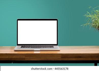 laptop blank screen on wooden table with green wall background