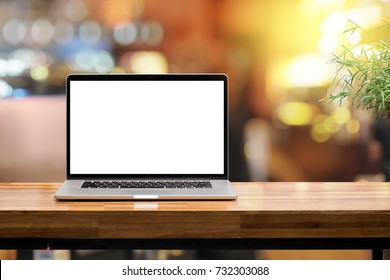 Laptop blank screen on wooden table blurred morning sunshine background