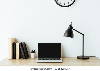 Laptop With Blank Screen On Work Desk In Front Of White Wall