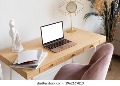 Laptop with blank white screen on the desk, mock up. Personal laptop computer on wood table in living room with modern interior.