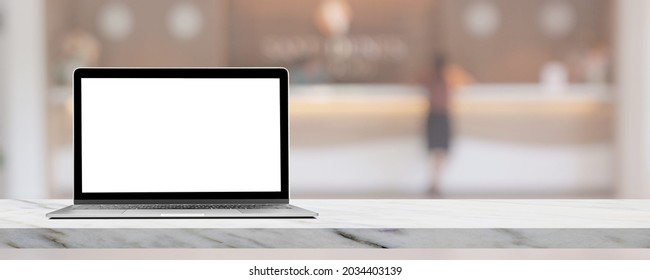 Laptop With Blank White Screen On Marble Table Top With Blurred Luxury Hotel Lobby Reception In The Background.