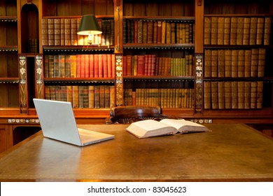 Laptop and book lying on a desk in classic library - Powered by Shutterstock