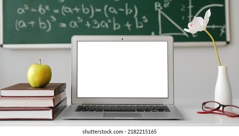 Laptop, Books And Apple On Teacher's Table In Classroom