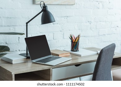 laptop, books, lamp and pencils on table in home office  - Shutterstock ID 1111174502