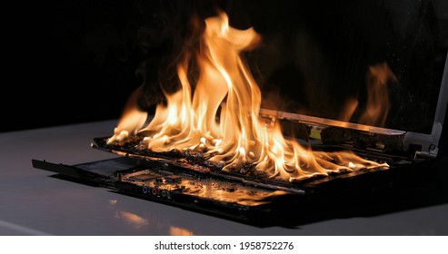 Laptop Burning In Flames On A Desk, Fire Hazard. Losing Valuable Data, Closeup