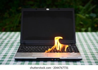 Laptop Burning In Flames On A Desk, Fire Hazard. Losing Valuable Data. Faulty Battery Failure. Computer Accident