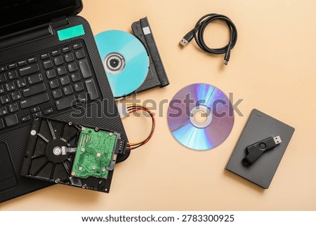 Laptop with CD disk and different memory storage devices on beige background
