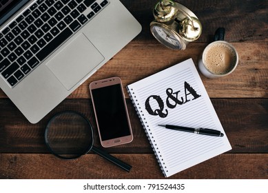 laptop, clock, phone, magnifying glass, coffee and notebook with Q&A word. Questions and answer concept