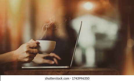 Laptop and coffee cup in girl's hands 