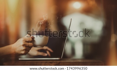 Laptop and coffee cup in girl's hands 