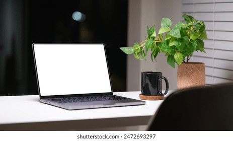 Laptop, coffee cup and potted plant on white table at night. Empty screen for your advertise design. - Powered by Shutterstock