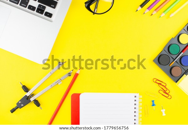 Laptop, colorful pensils, divider, black eye\
glasses and notepad planner on yellow background. Flat lay. Copy\
space. Workplace in the\
office