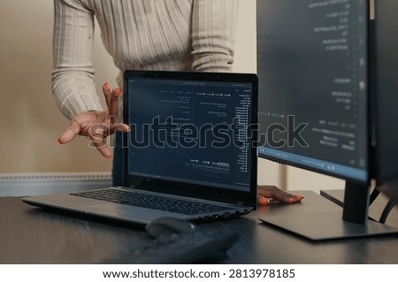 Laptop Compiling Algorithm Beside Developer Team in a software development office, showing programmers collaborating on source code, algorithms and data coding workflow.
