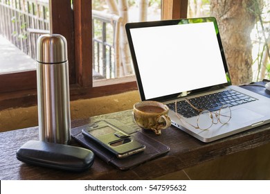laptop computer with blank empty screen for your information or contents cup of coffee and  smartphone on wood desk in cafe
