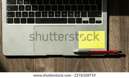 Laptop computer with blank post it note and pen on wooden table. Blank post it note on a computer. Copy space for text Office desk High angle view. Selective focus included