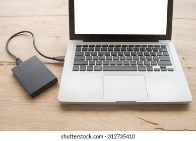 laptop computer with blank screen connecting to black external hard drive, with selective focus