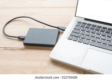 laptop computer with blank screen connecting to black external hard drive, with selective focus