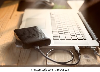 laptop computer with blank screen connecting to black external hard drive,  with selective focus