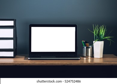 Laptop Computer With Blank Screen As Copy Space Placed On Office Desktop In Dark Interior.