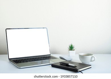 Laptop computer blank screen on white office desk table with coffee cup and notebook, mouse computer with equipment office supplies. Business and finance concept. Workplace, Flat lay with copy space.