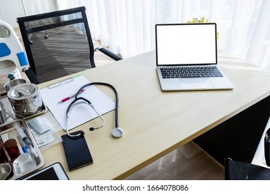 Laptop Computer With A Blank White Screen With Stethoscope,vial,syringe,empty Paper Clipboard And Medical Bottle Different Drugs On Surgical Tray With Medical Equipment On Wooden Table Background