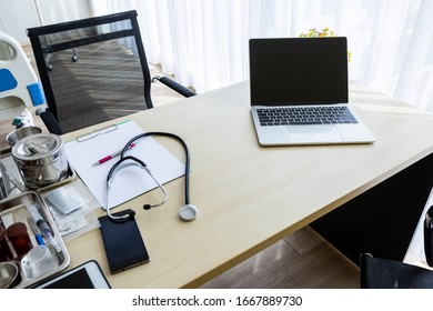 Laptop Computer With A Blank White Screen With Stethoscope,vial,syringe,empty Paper Clipboard And Medical Bottle Different Drugs On Surgical Tray With Medical Equipment On Wooden Table Background