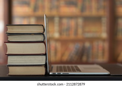 Laptop Computer And Book Stack On Desk In Library. Online Education And Lifelong Learning.