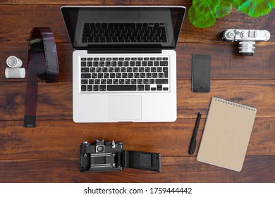 Laptop Computer, Camera, Roll Film, Notebook Blank And Smart Phone On Wood Table Top View With Copy Space