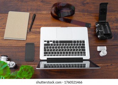 Laptop Computer, Camera, Roll Film, Notebook Blank And Smart Phone On Wood Table Top View With Copy Space