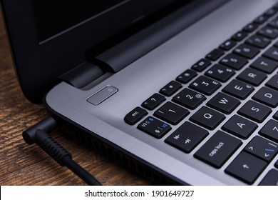 Laptop, computer is charging from a 220-volt outlet on a desk near the wall. Energy, accumulation