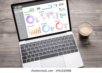 Laptop computer with CRM software on screen showing different graphs and business data