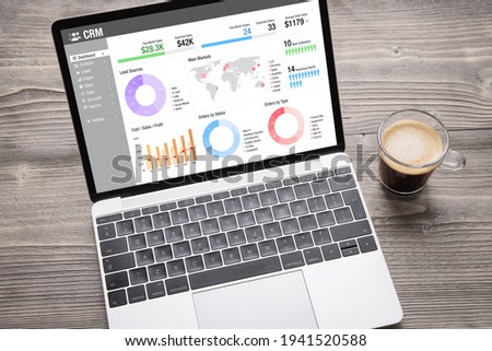 Laptop computer with CRM software on screen showing different graphs and business data